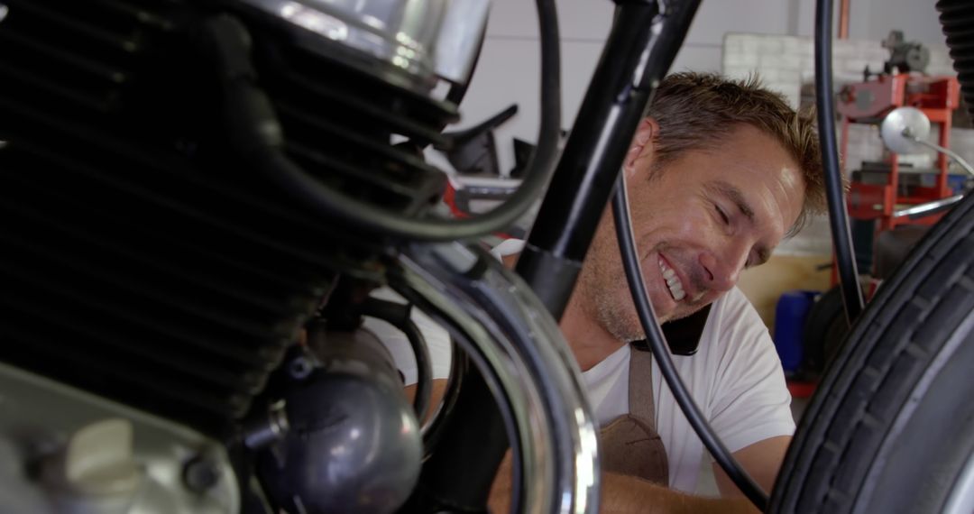 Male Mechanic Smiling While Repairing Motorcycle in Workshop - Free Images, Stock Photos and Pictures on Pikwizard.com