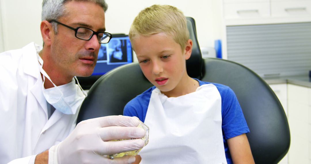 Dentist Explaining Procedure to Young Boy in Dental Clinic - Free Images, Stock Photos and Pictures on Pikwizard.com
