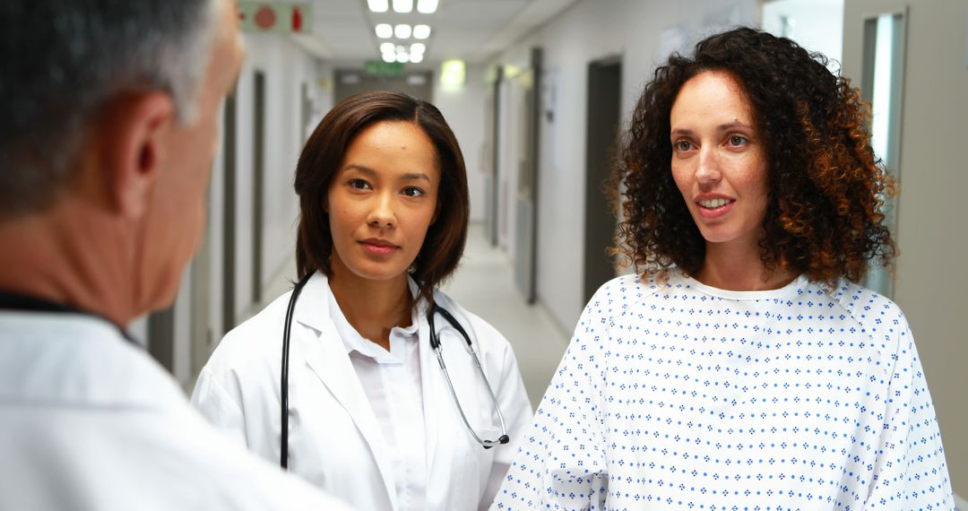 Doctors Discussing Treatment with Female Patient in Hospital Corridor - Free Images, Stock Photos and Pictures on Pikwizard.com