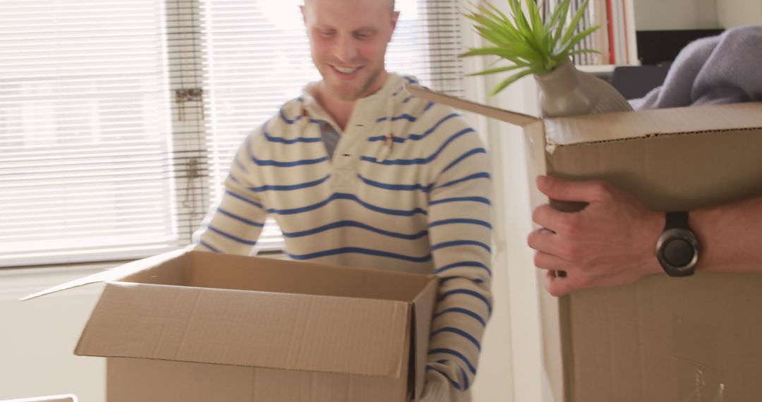 Smiling Man Unpacking Boxes in New Home - Free Images, Stock Photos and Pictures on Pikwizard.com