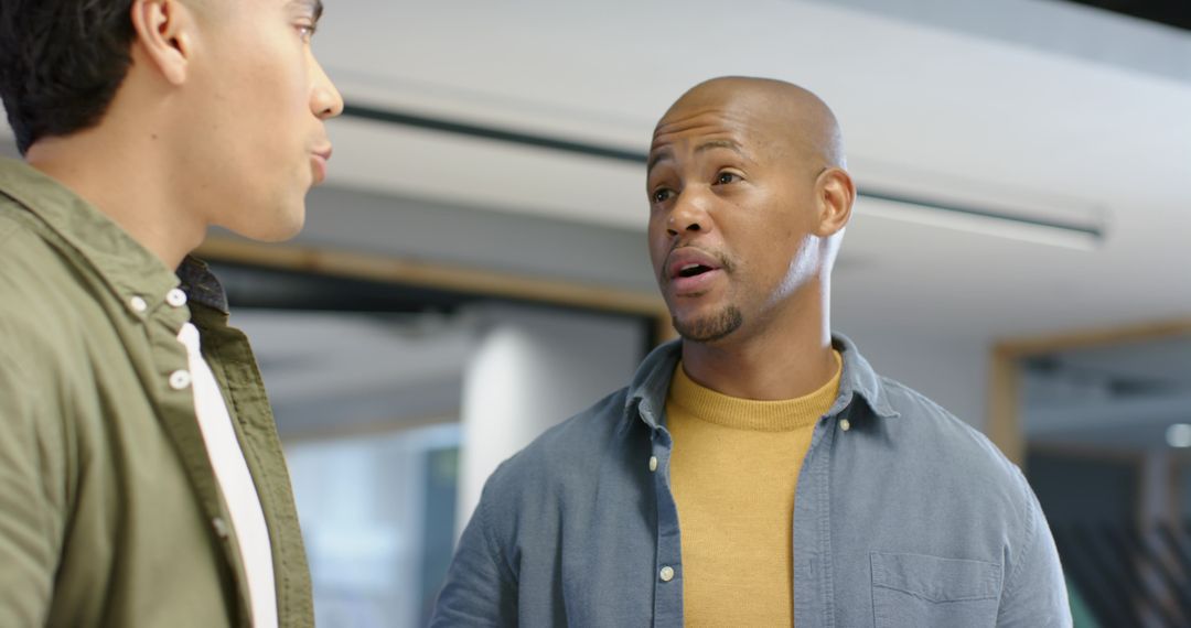 Coworkers Discussing Project in Modern Open-Plan Office, Mustard Sweater and Olive Jacket