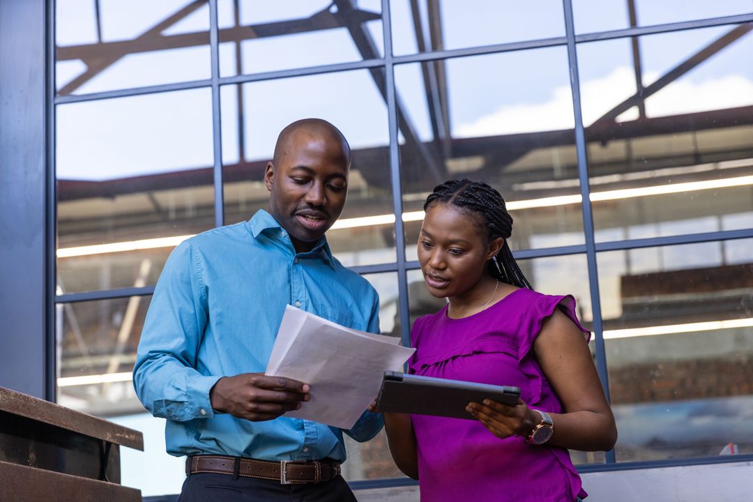 African American Colleagues Collaborating with Papers and Tablet in Modern Office