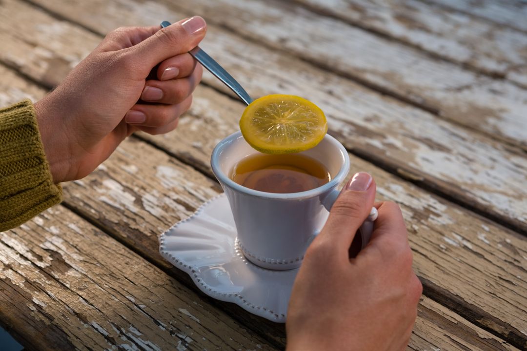 Woman Holding Lemon Slice Over Tea on Rustic Wooden Table - Free Images, Stock Photos and Pictures on Pikwizard.com