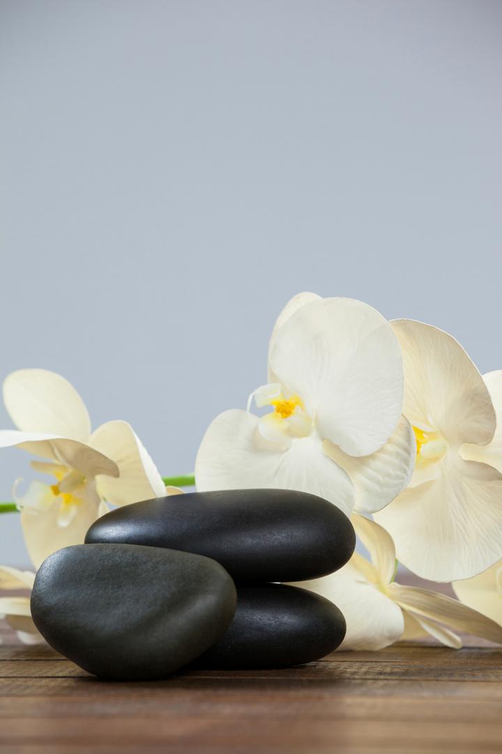 Stacked Pebble Stones with White Orchids on Wooden Table - Free Images, Stock Photos and Pictures on Pikwizard.com