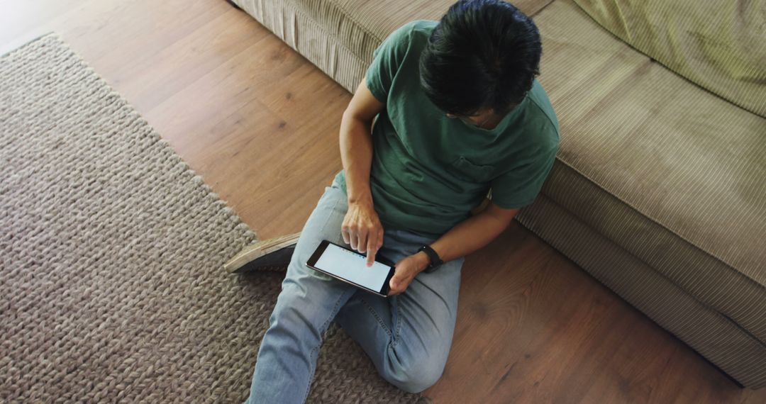 Young Man Using Tablet While Sitting on Floor at Home - Free Images, Stock Photos and Pictures on Pikwizard.com