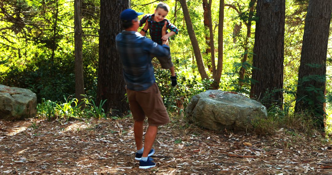 Father lifting young son in forest clearing during bright afternoon - Free Images, Stock Photos and Pictures on Pikwizard.com