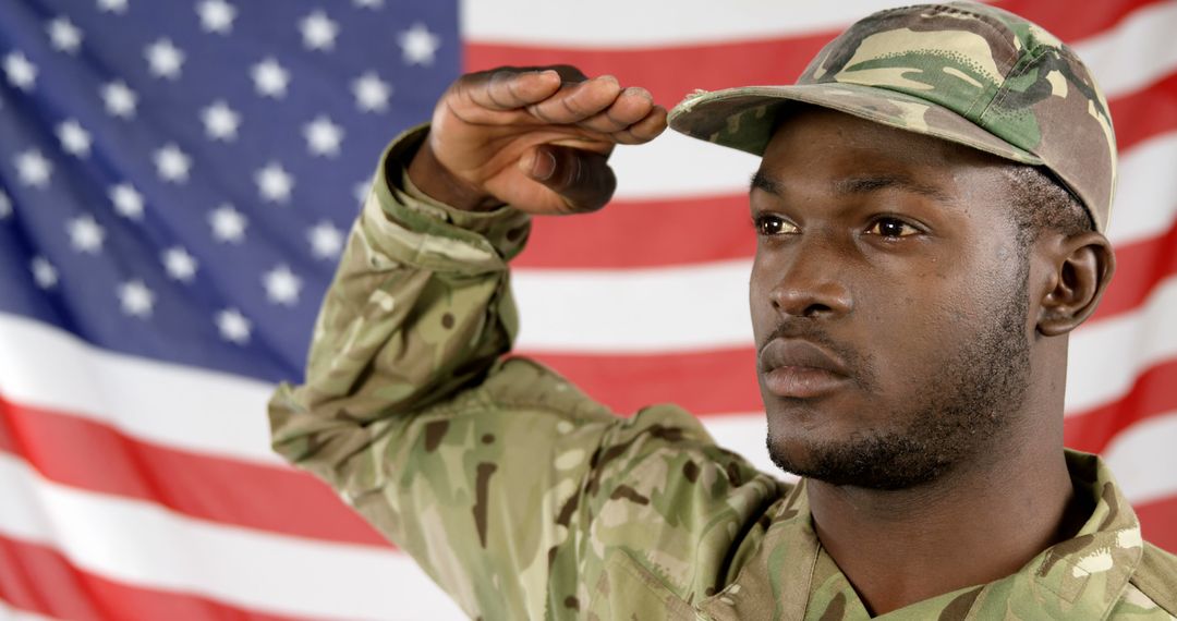 A solemn African American soldier salutes the American flag, embodying respect and patriotism. - Free Images, Stock Photos and Pictures on Pikwizard.com