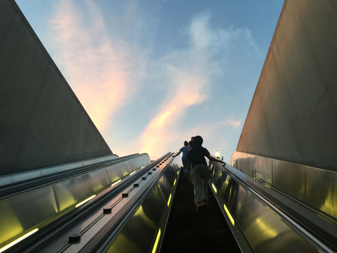 People Ascending Escalator During Sunset with Clear Sky - Free Images, Stock Photos and Pictures on Pikwizard.com