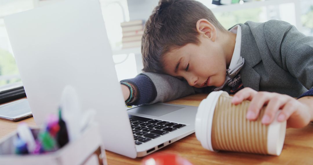 Exhausted Young Boy in Suit Sleeping at Desk with Coffee Cup