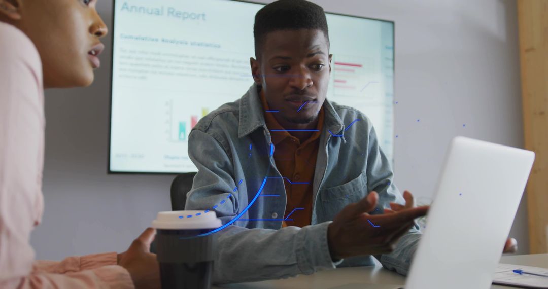Colleagues analyzing annual report with laptop and presentation screen during business meeting