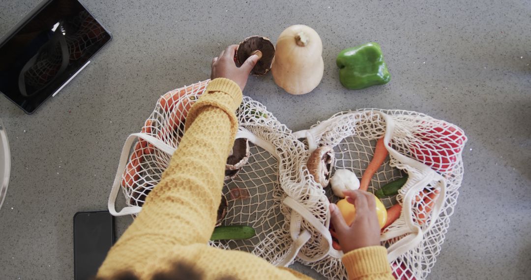 Top View of Person Placing Vegetables in Reusable Mesh Bag on Kitchen Counter - Free Images, Stock Photos and Pictures on Pikwizard.com