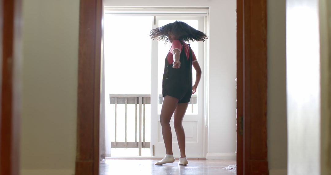 Young woman dancing joyfully in hallway near bright window - Free Images, Stock Photos and Pictures on Pikwizard.com