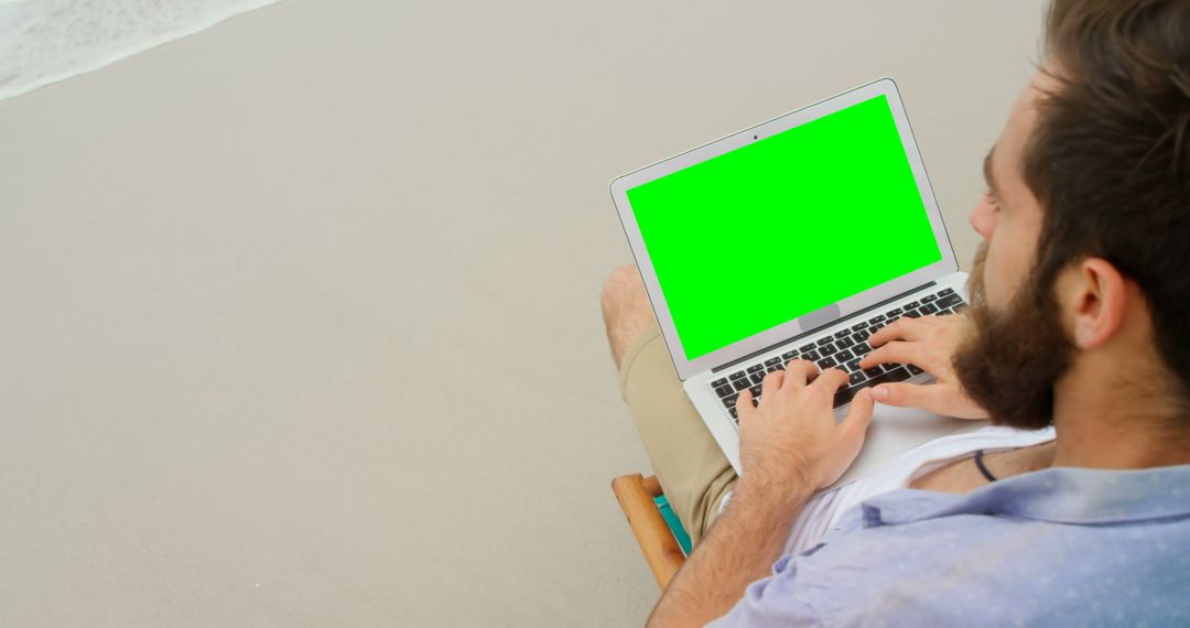 Man Relaxing on Beach with Laptop Featuring Green Screen