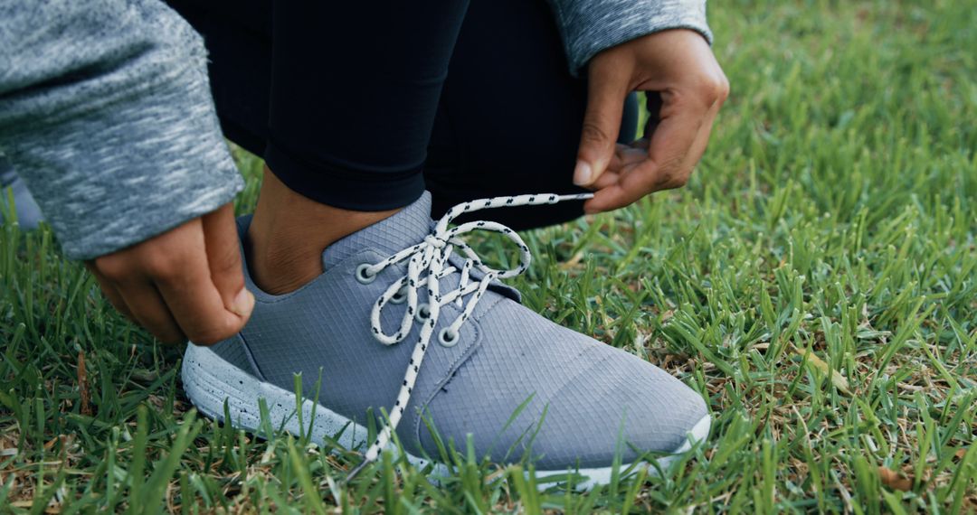 Person Tying Shoe Laces on Athletic Shoes in Grass Field - Free Images, Stock Photos and Pictures on Pikwizard.com