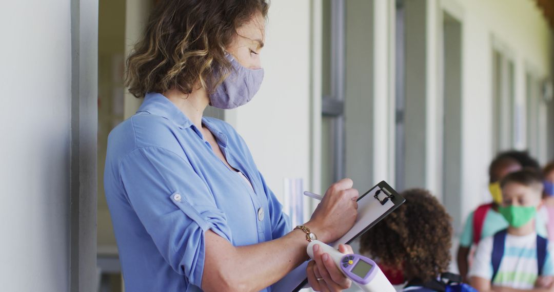 Teacher Checking Students' Temperatures During Return to School