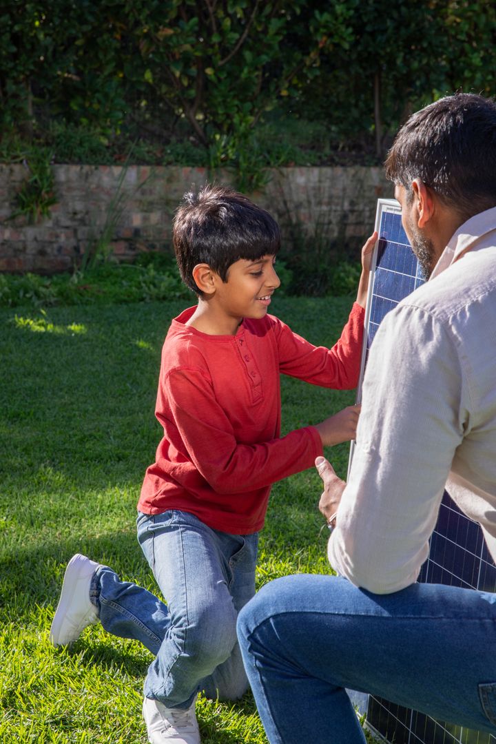 Father and Son Checking Solar Panel in Sunny Backyard