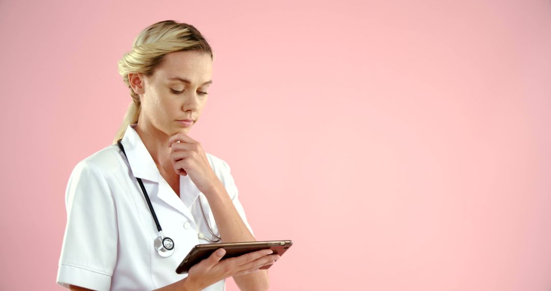 Young Nurse Thinking and Using Tablet Against Pink Background - Free Images, Stock Photos and Pictures on Pikwizard.com