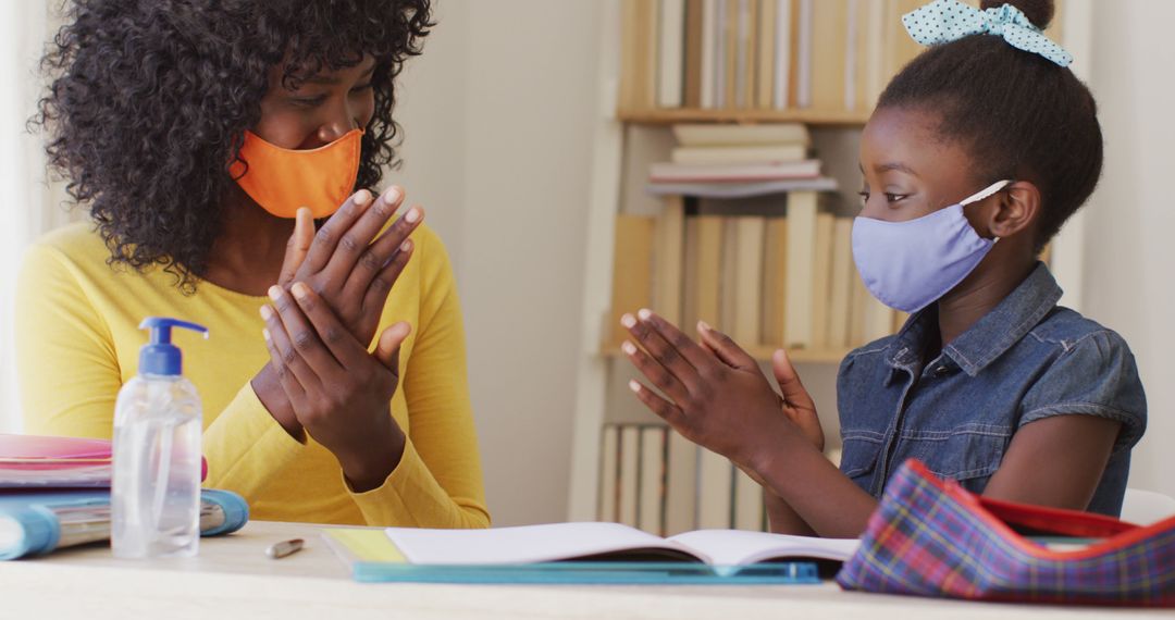 Mother and Daughter Sanitizing Hands with Protective Masks During Pandemic