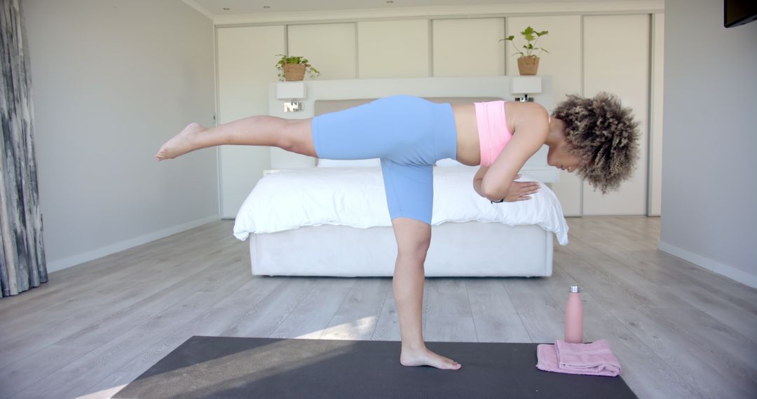 Woman Balancing in Yoga Pose On One Leg in Modern Bedroom