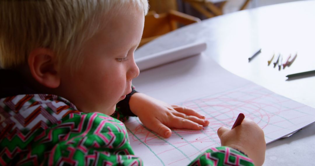 Young boy drawing with crayons at home creative playtime