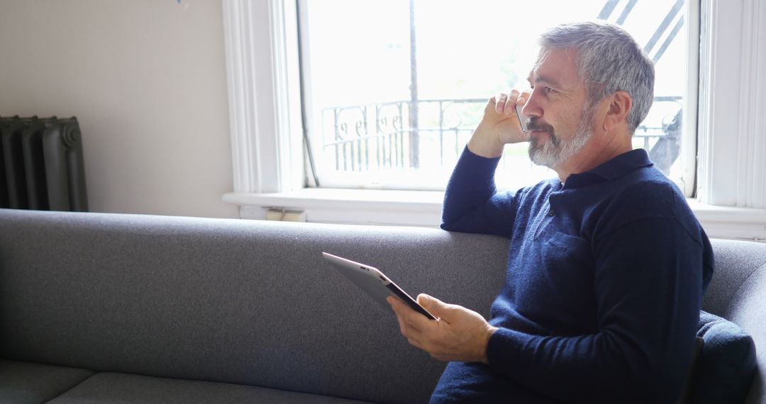 Senior Man Relaxing on Sofa While Holding Tablet - Free Images, Stock Photos and Pictures on Pikwizard.com