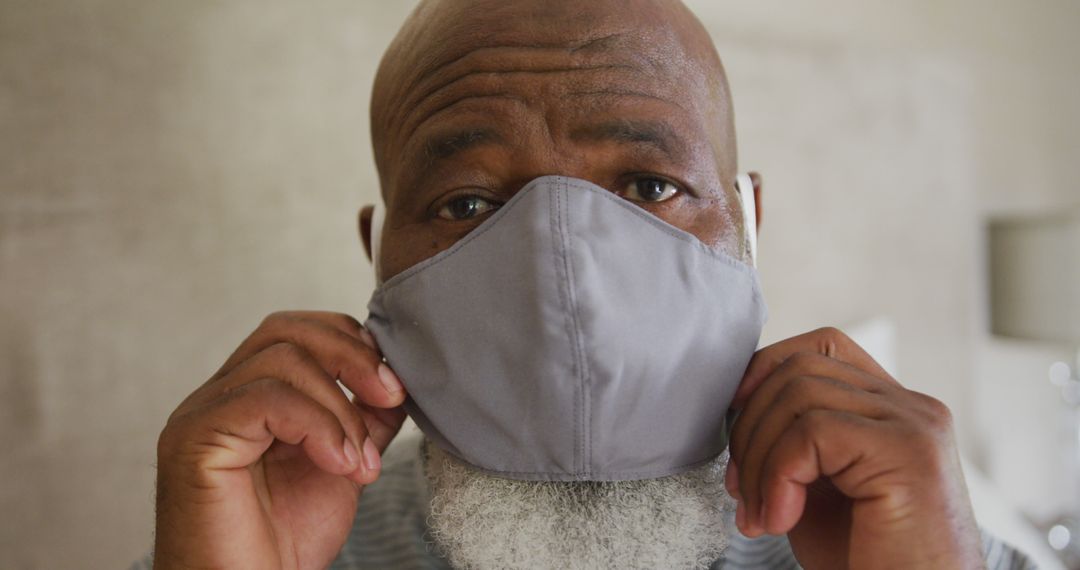 Elderly Man Adjusting Protective Face Mask Indoors - Free Images, Stock Photos and Pictures on Pikwizard.com