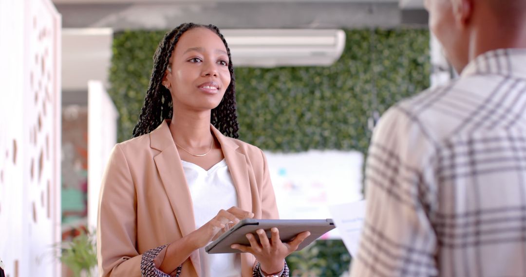 Confident Woman Presenting Idea with Tablet to Colleague in Modern Office