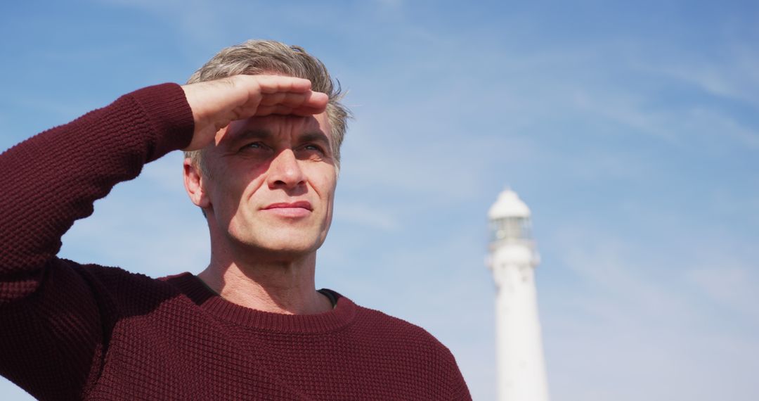 Man Gazing Into Distance in Front of Lighthouse on Clear Day - Free Images, Stock Photos and Pictures on Pikwizard.com