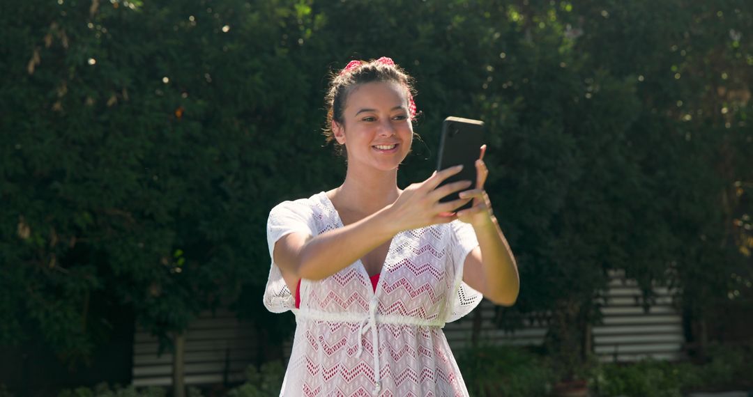 Smiling Woman Taking Selfie in Sunlit Garden