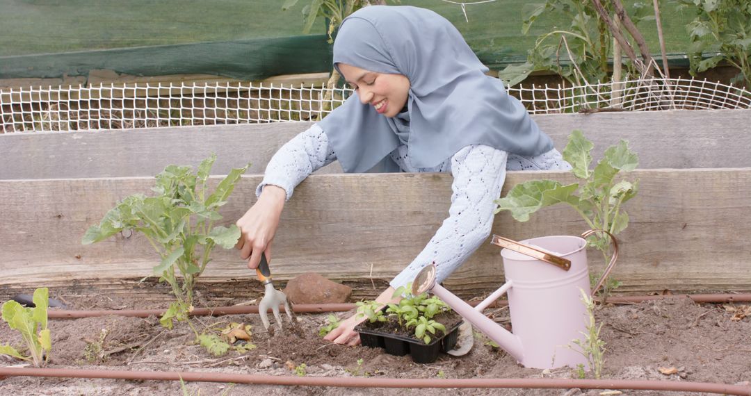 Smiling Woman in Hijab Gardening and Planting Flower Seedlings - Free Images, Stock Photos and Pictures on Pikwizard.com