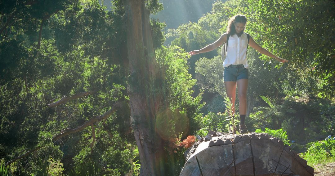 Young Girl Balancing on Log in Sunlit Forest