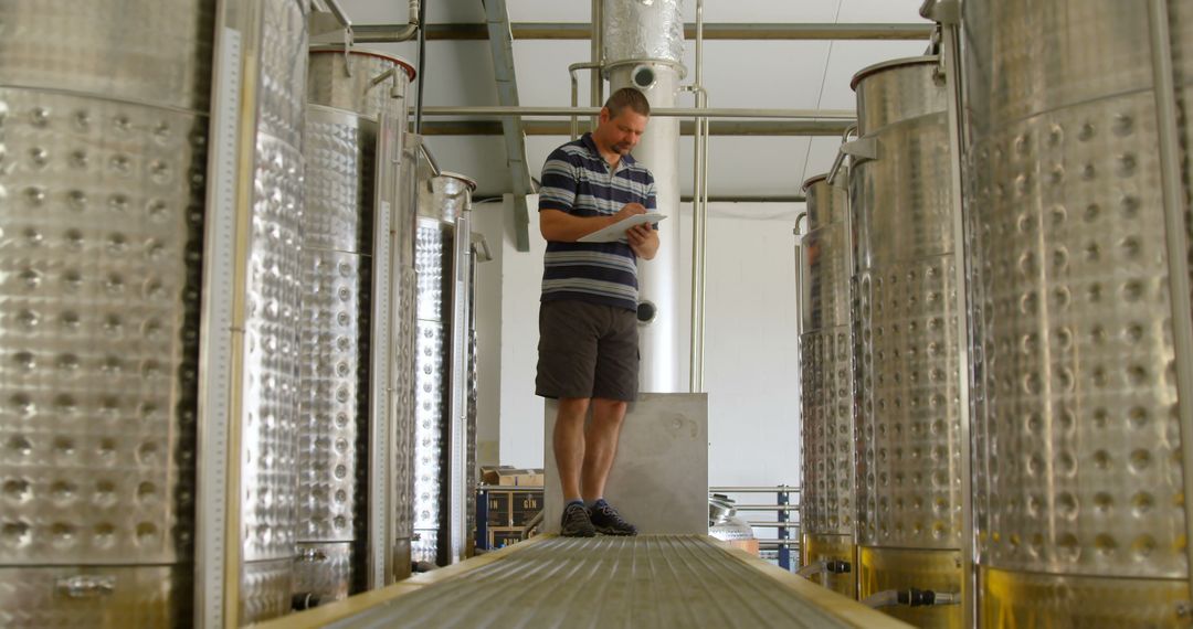 Man Inspecting Wine Fermentation Tanks in Modern Winery - Free Images, Stock Photos and Pictures on Pikwizard.com