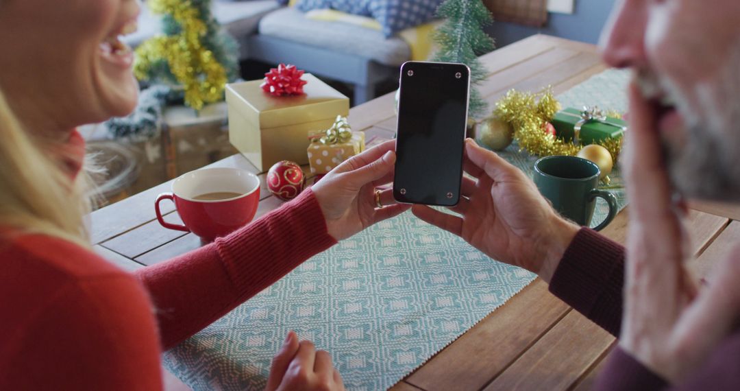 Couple Sharing Smartphone Excitedly During Holiday Season at Home - Free Images, Stock Photos and Pictures on Pikwizard.com