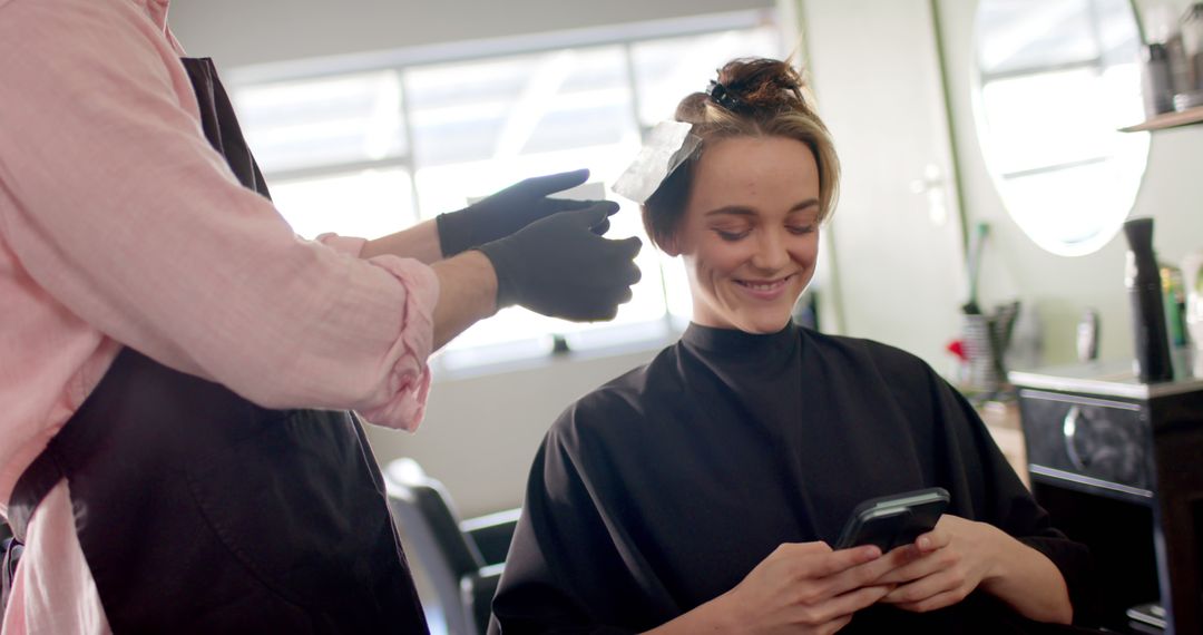 Woman Smiling While Using Phone at Hair Salon - Free Images, Stock Photos and Pictures on Pikwizard.com