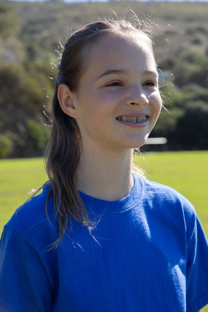 Teenage Girl with Braces Smiling in Sunlit Field