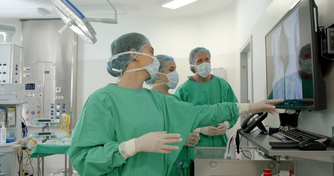 Medical Team in Surgical Attire Consulting Monitors in Operating Room - Free Images, Stock Photos and Pictures on Pikwizard.com