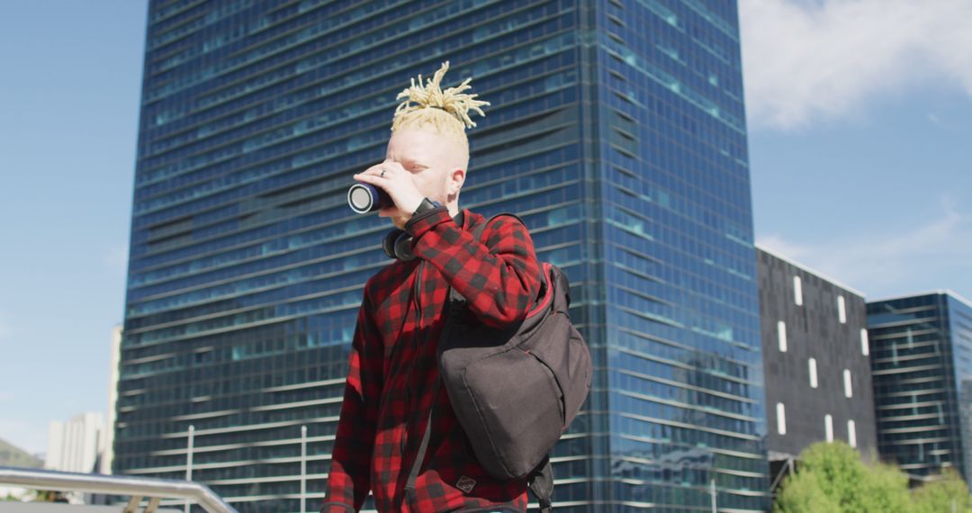 Young Man with Dreadlocks Enjoying Coffee in Modern Cityscape