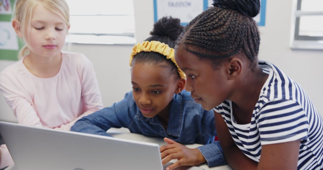 Diverse Female Students Collaborating Around Laptop in Classroom