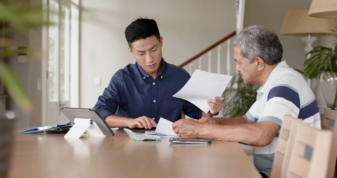 Young Man Assisting Elderly Father with Financial Documents at Home - Free Images, Stock Photos and Pictures on Pikwizard.com