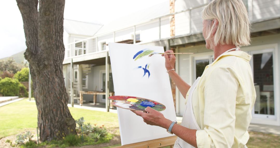 Senior Woman Painting Outdoors on Sunny Day - Free Images, Stock Photos and Pictures on Pikwizard.com