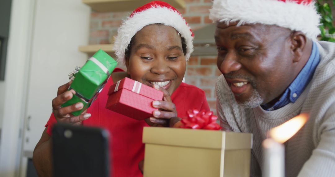 Happy Elderly Couple Wearing Santa Hats Opening Christmas Gifts - Free Images, Stock Photos and Pictures on Pikwizard.com