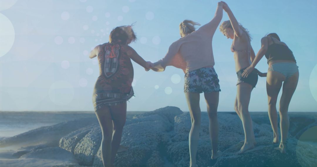 Friends Enjoying a Beach Day and Jumping on Rocks