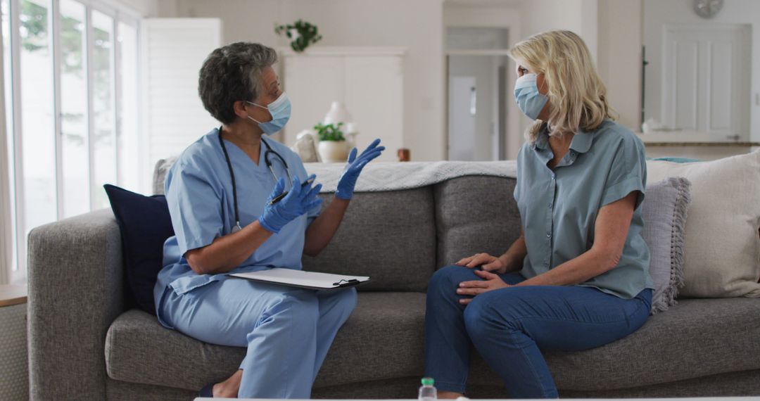 Female Doctor Consults with Senior Patient in Living Room While Wearing Masks - Free Images, Stock Photos and Pictures on Pikwizard.com