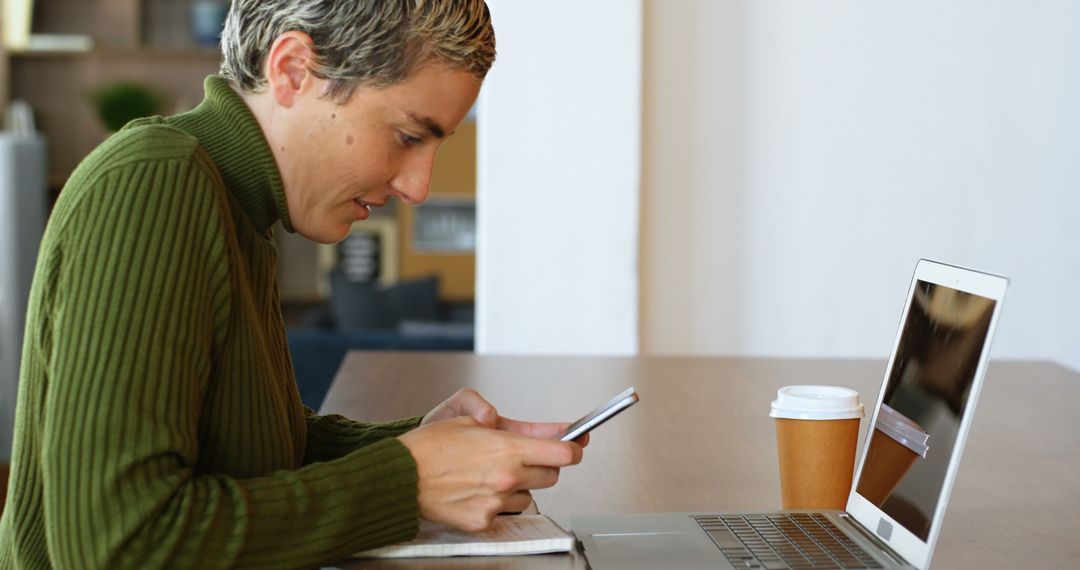 Person Typing on Smartphone while Seated at Desk with Laptop and Coffee - Free Images, Stock Photos and Pictures on Pikwizard.com