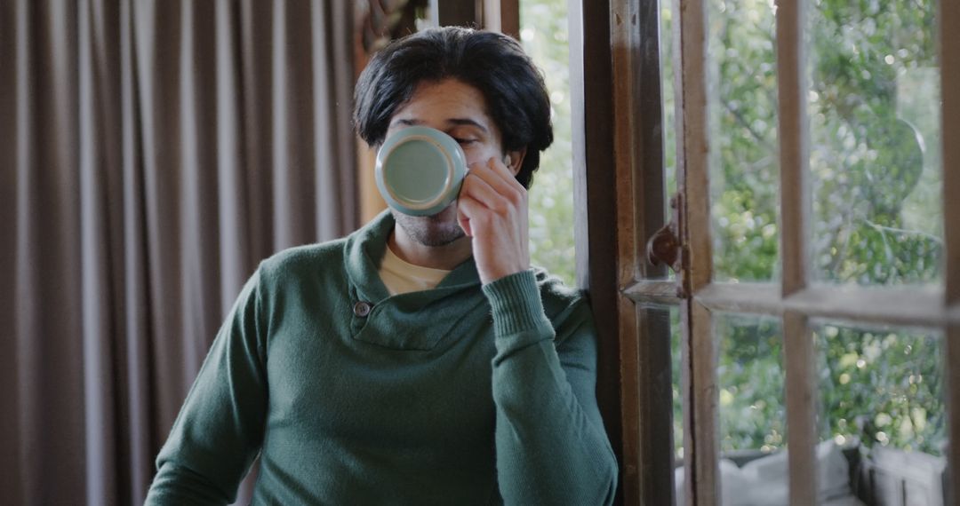 Man drinking morning coffee by window in cozy home - Free Images, Stock Photos and Pictures on Pikwizard.com