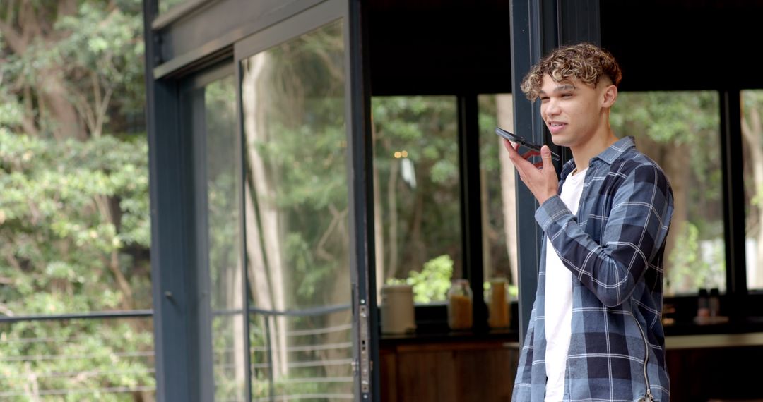 Man Using Smartphone for Voice Command on Sunny Balcony