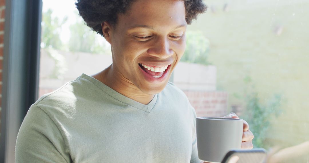 Man Enjoying Coffee and Using Smartphone at Home