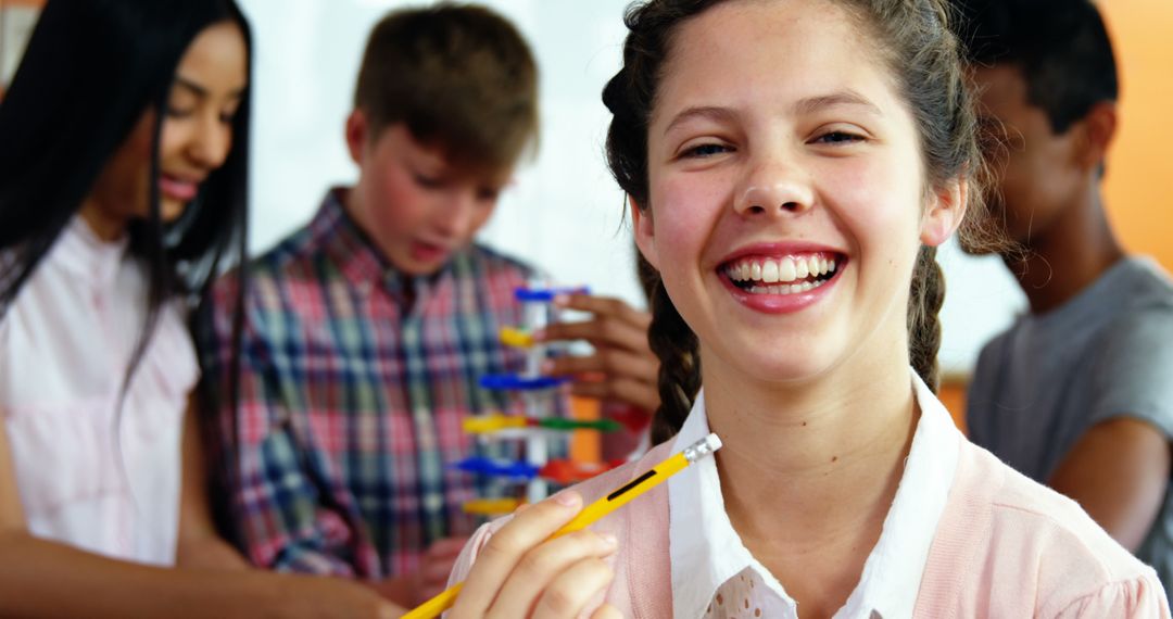 Cheerful Schoolgirl Holding Pencil in Classroom with Classmates - Free Images, Stock Photos and Pictures on Pikwizard.com