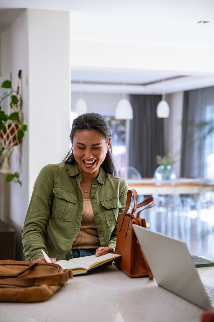 Asian Woman Taking Notes Smiling Laptop Modern Lounge Cafe