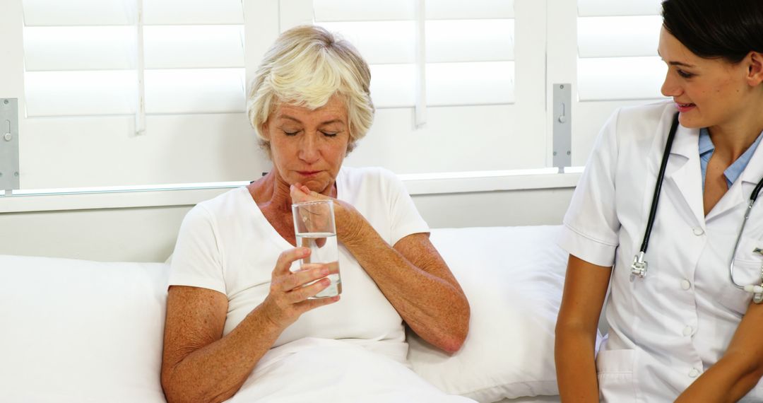 Nurse Comforting Senior Woman Drinking Water in Bed - Free Images, Stock Photos and Pictures on Pikwizard.com